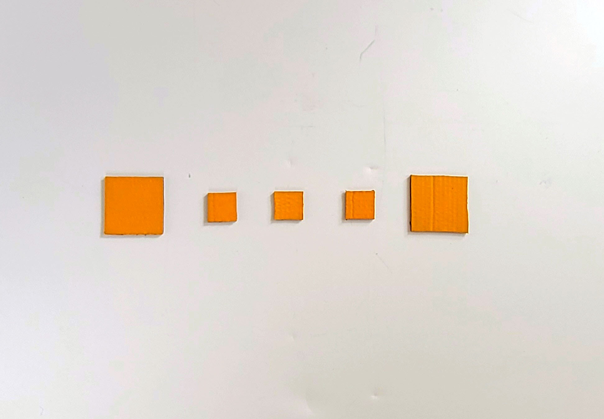 Image of artwork, Oscillation – Golden, 2024. Oscillation - Golden consists of 5 squares, the first square 4in x 4in, followed by three smaller squares that measure 2in x 2in, and followed by the remaining square which is also 4in x 4in. Each square is painted with an golden acrylic paint.